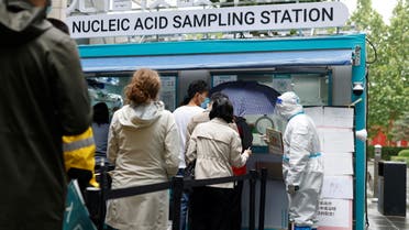 People line up to get tested next to a staff member wearing personal protective equipment (PPE) at a mobile nucleic acid testing site outside a shopping mall, amid the coronavirus disease (COVID-19) outbreak in Beijing, China May 6, 2022. (Reuters)