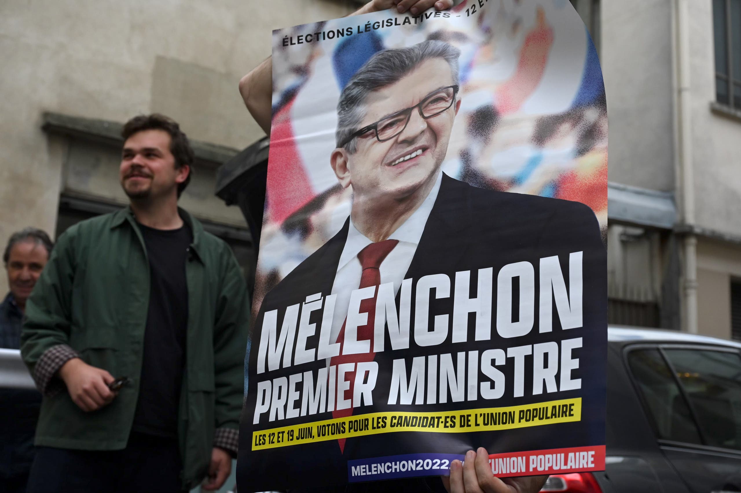 A supporter of the French left raises a banner calling for Melenchon to be named prime minister
