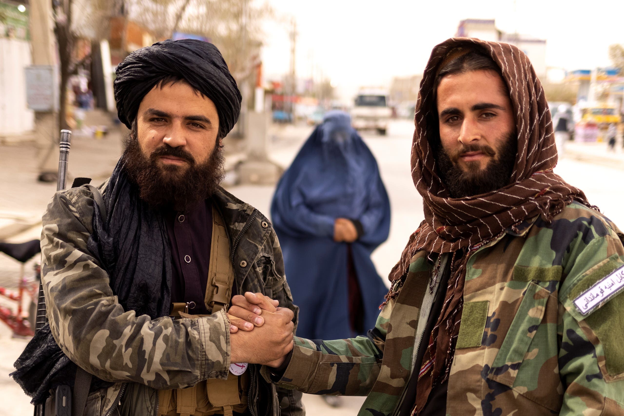 Two Taliban fighters in Kabul last October, with a woman wearing a burqa behind them