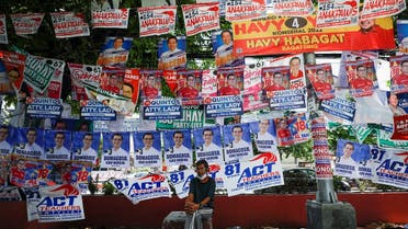 A man sits below election posters a day prior to the national elections in Manila, Philippines, on May 8, 2022. (Reuters)