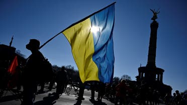 A protester holds a Ukrainian flag during a demonstration against Russia's invasion of the Ukraine, near the Victory Column in Berlin on March 13, 2022. (AFP)