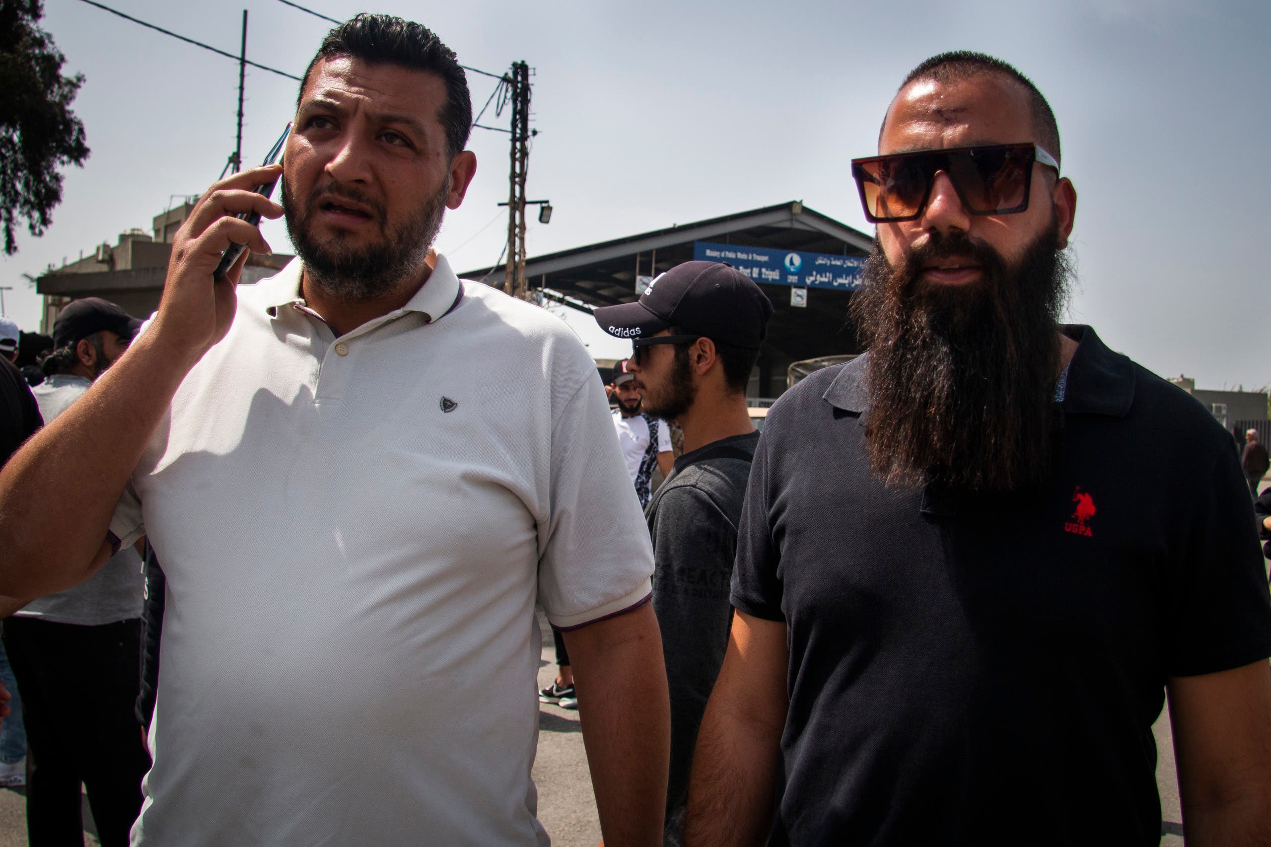 Shadi al-Jundi (right) lost his two sisters when the migrant boat they were on capsized. He stands next to a family member at the entrance to the international port of Tripoli to ask the government to maximize its search efforts for victims. (Photo: Sally Abou Al Joud)