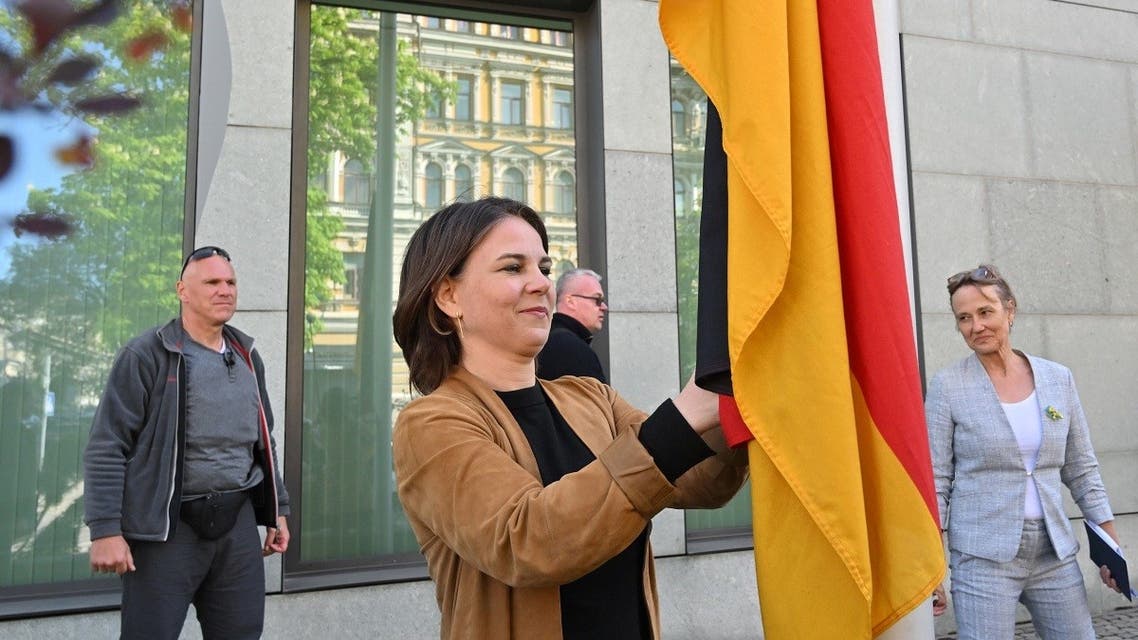 German Foreign Minister Annalena Baerbock rises up the national German flag outside the German embassy in Kyiv on May 10, 2022 as she announced its reopening in the Ukrainian capital. (AFP)