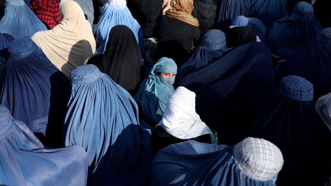 A girl sits in front of a bakery in the crowd with Afghan women waiting to receive bread in Kabul, Afghanistan, January 31, 2022. REUTERS/Ali Khara/File Photo