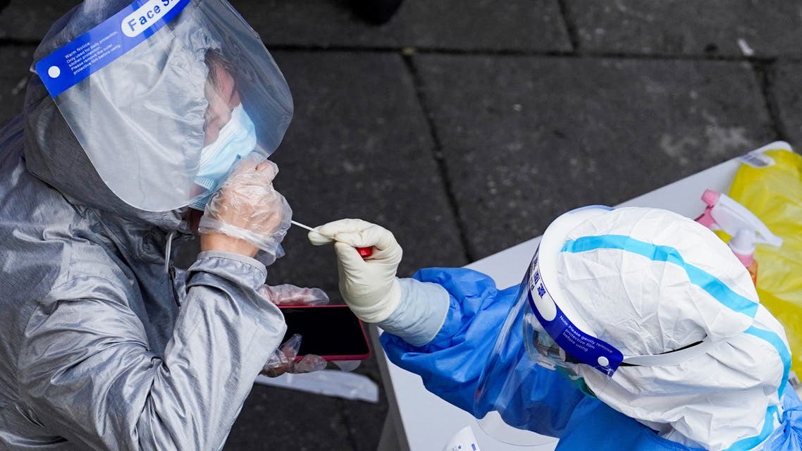A worker collects a swab sample from a resident at a nucleic acid testing site during a lockdown, amid the coronavirus outbreak, in Shanghai, China, April 28, 2022. (Reuters)