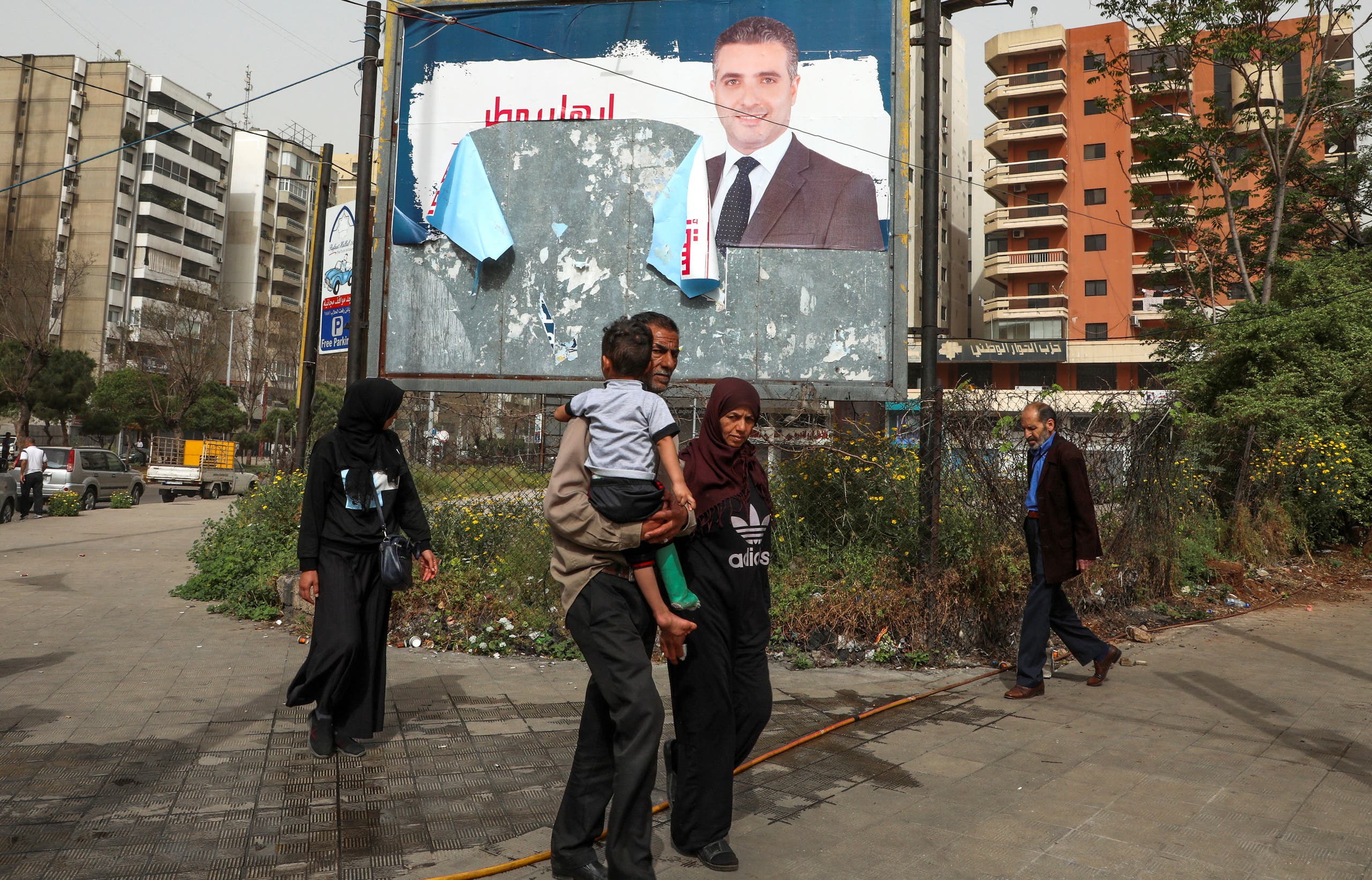 People walk past a torn campaign banner, ahead of parliamentary election that are scheduled for May 15, in Tripoli, Lebanon April 25, 2022. (File photo: Reuters)