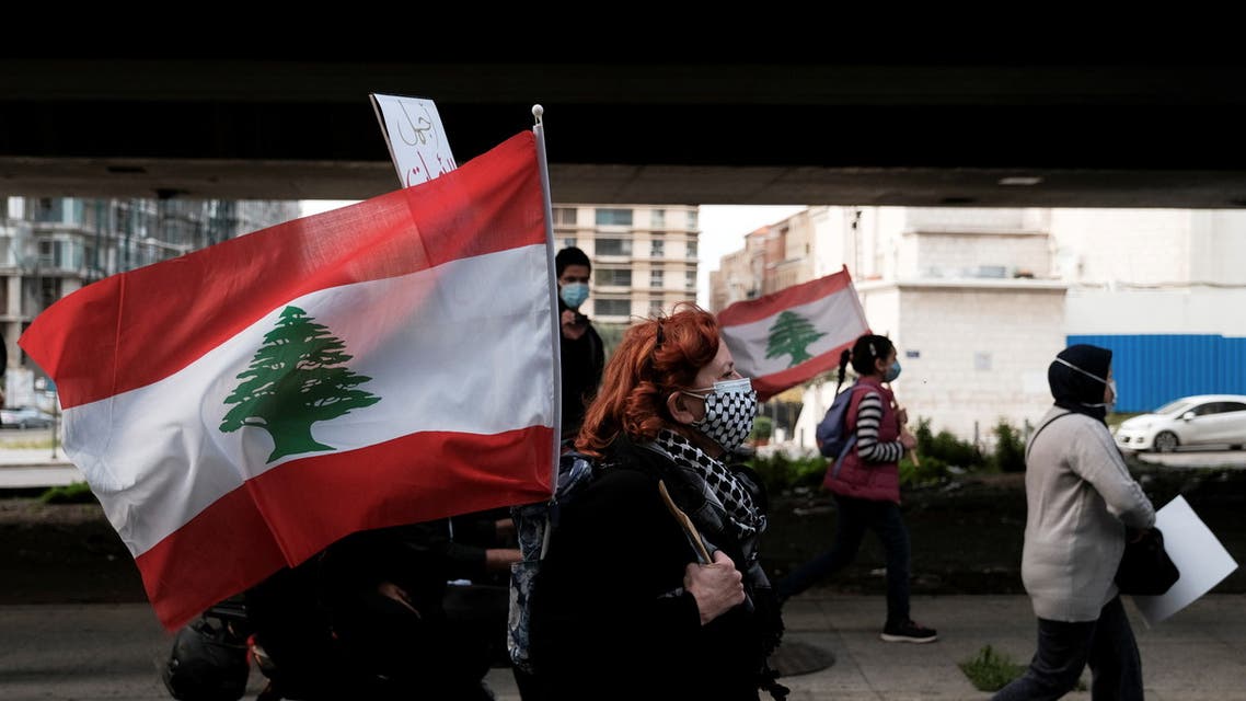 A Lebanese mother walks with a national flag as she takes part in a march against the political and economic situation, ahead of Mother's Day in Beirut, Lebanon March 20, 2021. (Reuters)