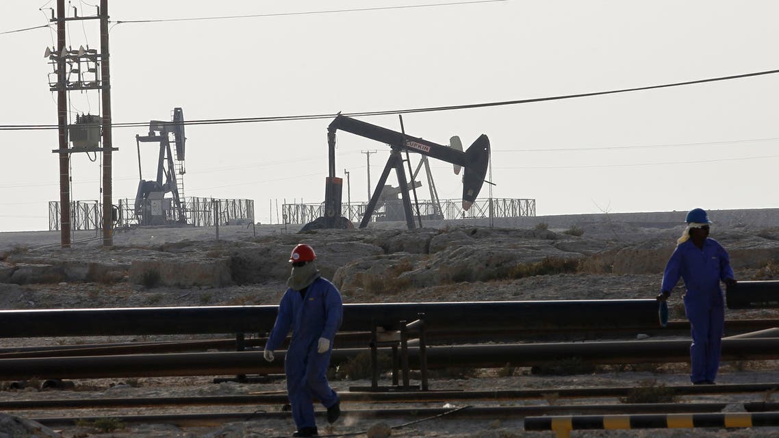 Oil company workers walk as oil pipes and oil pumps are seen in the background in Sakir, south of Manama, October 11, 2014. (File photo: Reuters)