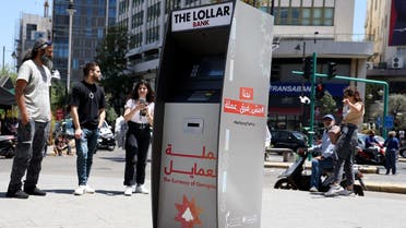 Lebanese surround a mock ATM, distributing fake banknotes called “Lollars,” during a stunt to denounce the high-level of corruption that has wrecked the country, in the capital Beirut, on May 13, 2022. (AFP)