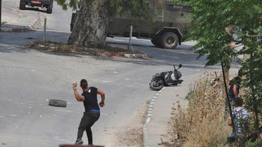A Palestinian youth throws a stone during clashes with Israeli security forces in the West Bank city of Jenin, on May 13, 2022. (AFP)