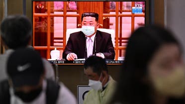 People sit near a screen showing a news broadcast at a train station in Seoul on May 12, 2022, of North Korea’s leader Kim Jong Un appearing in a face mask on television for the first time to order nationwide lockdowns after the North confirmed its first-ever Covid-19 cases. (AFP)