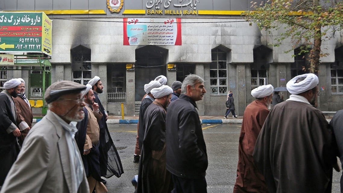 A file photo shows Iranians walk past the branch of a local bank that was damaged during demonstrations against petrol price hikes, on November 20, 2019 in Shahriar, west of Tehran. (AFP)
