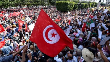 Tunisian protesters wave flags and raise placards as they demonstrate against their president in the capital Tunis, on May 15, 2022. Last July, Tunisian President Kais Saied abruptly suspended the mixed presidential-parliamentary system enshrined in Tunisia's 2014 constitution, a hard-won compromise between rival ideological camps reached three years after a revolt toppled dictator Zine El Abidine Ben Ali. (Photo by FETHI BELAID / AFP)