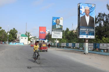 A Somali man cycles past election banners of presidential candidates along a street in Mogadishu on May 13, 2022. (Photo by Hassan Ali ELMI and Hassan Ali ELMI / AFP)
