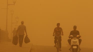 People cross a bridge during a sandstorm in Baghdad, Iraq, May 16, 2022. (Reuters)
