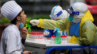 A medical worker in a protective suit collects a swab sample from a chef for nucleic acid testing, during lockdown, amid the coronavirus pandemic, in Shanghai, China, on May 13, 2022. (Reuters)
