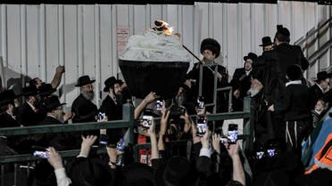 An Ultra-Orthodox Jewish rabbi lights up a bonfire at the grave site of Rabbi Shimon Bar Yochai at Mount Meron in northern Israel on April 29, 2021 as the ultra-Orthodox celebrate the Jewish holiday of Lag BaOmer. (AFP)