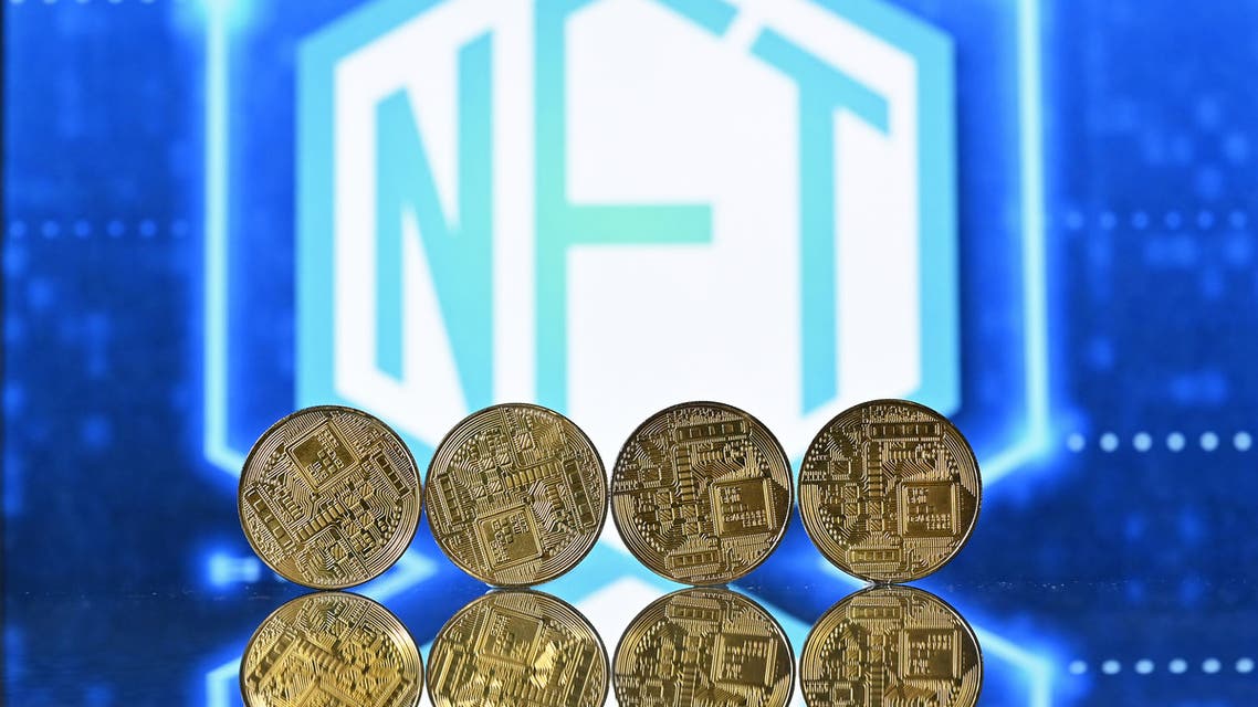 An illustration picture taken in London on December 30, 2021, shows gold plated souvenir cryptocurrency coins arranged by a screen displaying a NFT (Non-Fungible Token) logo. (AFP)