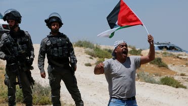 A Palestinian man shouts while holding a flag as he takes part in a protest, after Israeli top court paved way for razing eight Palestinian hamlets, in Masafer Yatta, south of Hebron, in the Israeli-occupied West Bank May 20, 2022. (Reuters)