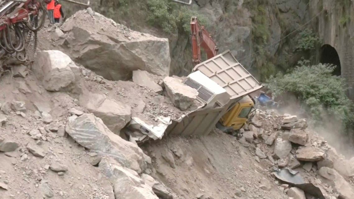 A crane removes debris from around a trapped vehicle after the collapse of a tunnel under construction in Ramban, Jammu and Kashmir, May 20, 2022, in this still image obtained from a video. (ANI/Handout via Reuters)