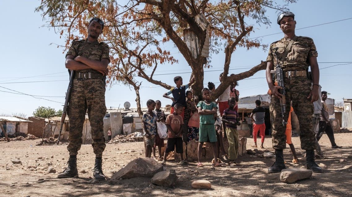 Ethiopian Army soldiers stand as a children stand behind them at Mai Aini Refugee camp, in Ethiopia, on January 30, 2021. (AFP)