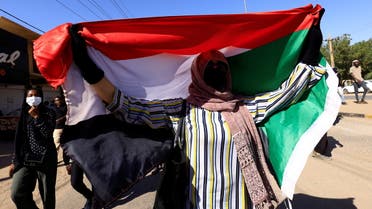 A person holds up Sudan's flag as protesters march during a rally against military rule, following last month's coup in Khartoum North, Sudan, January 6, 2022. REUTERS/Mohamed Nureldin Abdallah