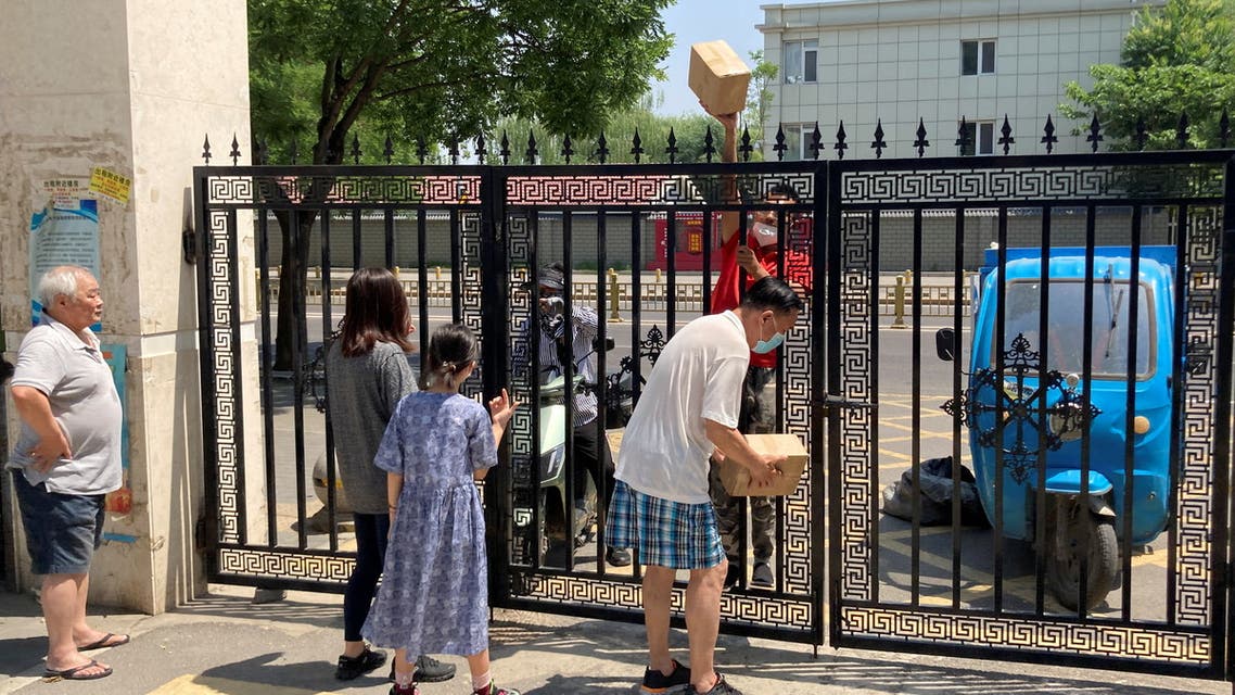 A courier hands parcels through a closed gate of a residential compound where delivery workers are not allowed to enter, amid the coronavirus disease (COVID-19) outbreak, in Beijing, China May 22, 2022. (Reuters)