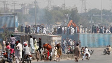 Supporters of the Pakistan Tehreek-e-Insaf (PTI) political party use a crane to remove shipping containers, used to block the roads to prevent them from attending the protest march planned by ousted Prime Minister Imran Khan in Islamabad, in Rawalpindi, Pakistan on May 25, 2022. (Reuters)
