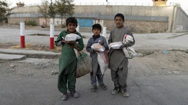 Children pose for a photo after receiving bags of food, in front of the concrete wall of a former U.S. army base in Kabul, Afghanistan, October 16, 2021. (File photo: Reuters)