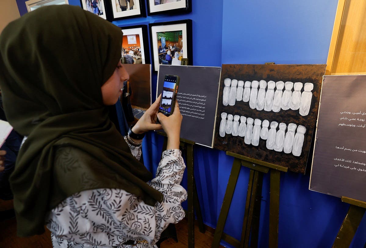 A Palestinian girl takes a picture during an exhibition of Zainab al-Qolaq, 22-year-old Gazan artist, in Gaza City May 24, 2022.  (Reuters)
