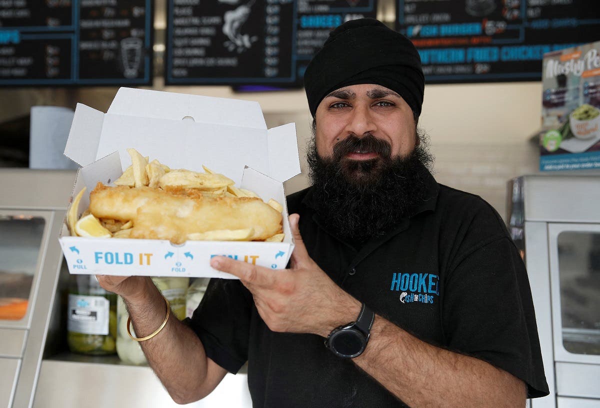 Owner of Hooked Fish and Chips shop, Bally Singh, holds a portion of fish and chips at his take-away in West Drayton, Britain, on May 25, 2022. (Reuters)