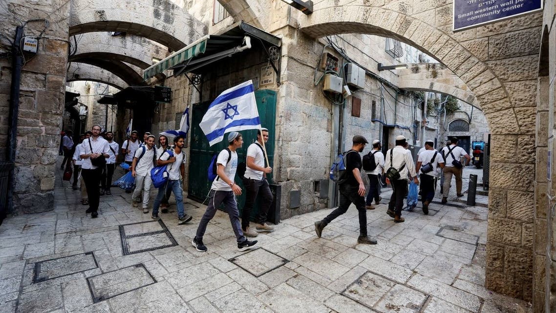 Jewish men carry Israeli national flags as they walk in an alley, inside Jerusalem's Old city May 29, 2022. REUTERS/Ammar Awad