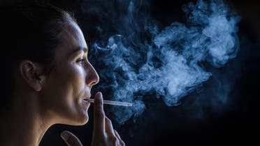 Profile view of beautiful woman smoking in the dark. stock photo