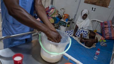 A nurse prepares food as a mother looks on at her malnourished child in the emergency medial care section for critical care patients in the ALIMA (The Alliance for International Medical Action) managed nutrition unit of the hospital Tchad/ Chine in N'djamena, Chad on May 13, 2022. (AFP)