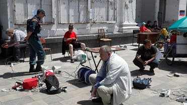 People charge their electronic devices in front of a theatre building destroyed during Ukraine-Russia conflict in the southern port city of Mariupol, Ukraine May 30, 2022. (File photo: Reuters)