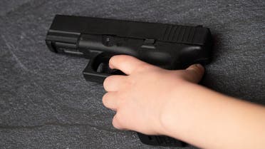 Young Caucasian White Child Kid Boy Hand Holding Black Gun Firearm Weapon stock photo
