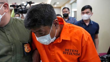 Immigration officers escort Mitsuhiro Taniguchi, 47, of Japan, left, during a press conference at immigration office in Jakarta, Indonesia Wednesday, June 8, 2022. Authorities on the southern tip of Indonesia's Sumatra island arrested a Japanese fugitive accused of fraud in Japan in connection with the receipt of a massive amount of COVID-19 subsidies for small businesses in distress, police said Wednesday.(AP Photo/Achmad Ibrahim)