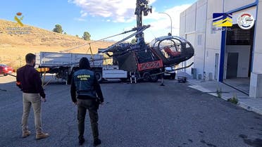 In this handout image released by Guardia Civil on January 9, 2022 a helicopter used to smuggle drugs is loaded on a truck by police after being seized in Torremolinos, Spain. (AFP)
