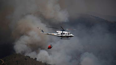 A helicopter participating in fire containment in Sierra Bermeja mountain range in Malaga is pictured from Benahavis on June 9, 2022. (AFP)
