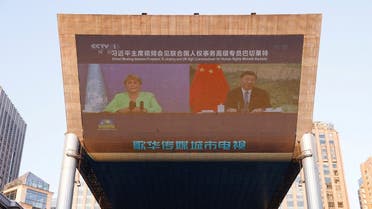 Chinese President Xi Jinping and the top UN official for human rights Michelle Bachelet are seen on a giant screen broadcasting news footage of their virtual meeting in Beijing, May 25, 2022. (Reuters)
