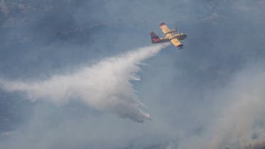 A plane drops water onto a forest fire in the Sierra de Leyre mountain range, Yesa, Spain. June 15, 2022. (Reuters)