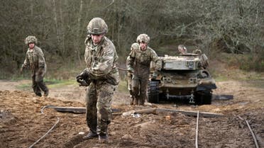Soldiers carry cables as they take part in a training exercise to winch and recover a stranded battle tank during the Royal Electrical & Mechanical Engineers’ Exercise called Iron Challenge at the Longmoor training area, near Bordon, Hampshire, on March 14, 2022. (AFP)