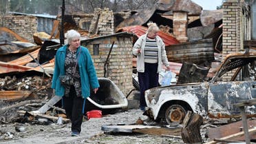 Nadiya (L), and Natalia (R), both 62, walk amid debris of their destroyed houses in the village of Moshchun, northwest of Kyiv, on April 20, 2022, as more than five million Ukrainians have now fled their country following the Russian invasion, the United Nations says. (AFP)