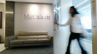 Logo of Mumtalakat is seen as an employee walks out at their headquarters Manama, Bahrain February 21, 2018. (File photo: Reuters)