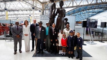 Britain's Prince William (3rdL), Duke of Cambridge, Britain's Catherine (2ndL), Duchess of Cambridge, Baroness Floella Benjamin (R), Windrush passengers Alford Gardner (C) and John Richards (4thL) and children pose for a picture with the National Windrush Monument created by Jamaican artist Basil Watson (L) at Waterloo Station in London on June 22, 2022. (AFP)