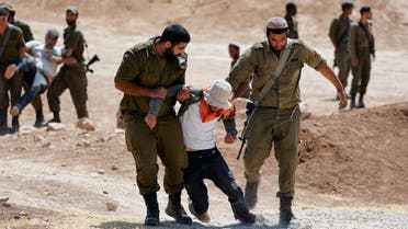 Israeli soldiers detain an activist during a protest against the Israeli military drill, in Masafer Yatta, in the Israeli-occupied West Bank on June 22, 2022. (Reuters)