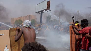 Anti-coup protesters take cover as riot police try to disperse them with water cannon and tear gas during a demonstration against military rule in the centre of Sudan's capital Khartoum on June 30, 2022. (AFP)