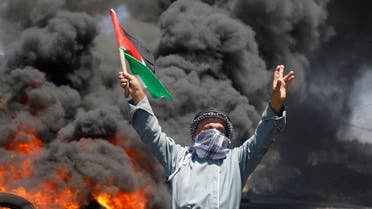 A man holds a Palestinian flag during a protest against Israeli settlement activity in Kafr Qaddum in the Israeli-occupied West Bank on July 1, 2022. (Reuters)
