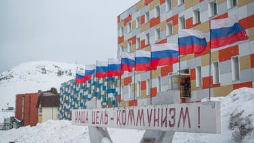 In this file photo taken on May 07, 2022 a sign in Russian reading ‘our goal is communism’ is pictured in front of a building with Russian flags flapping in the blizzard, in the miners’ town of Barentsburg, on the Svalbard Archipelago, northern Norway. (AFP)