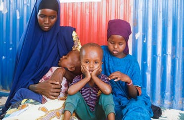 Amina Hassan Aden sits with her children Yonis Saleban, 1, Abdulahi Saleban, 3, and Isnino Saleban, 9, inside their makeshift shelter at the Kaxareey camp for the internally displaced people in Dollow, Gedo region of Somalia May 24, 2022. (Reuters)
